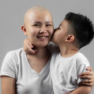 image of bald woman being kissed on cheek by her son